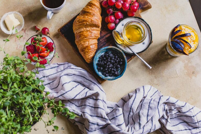 A delicious rustic breakfast spread with croissants, berries, and honey on a table setting.