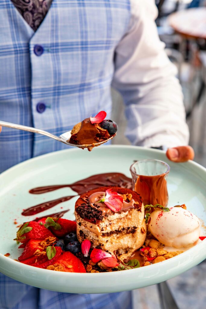 Gourmet dessert with berries, chocolate sauce, and ice cream on a plate, elegantly served.